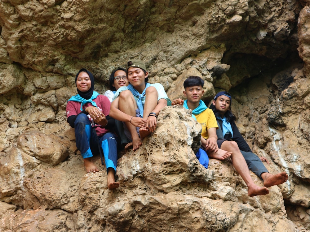 a group of people sitting on top of a rocky cliff