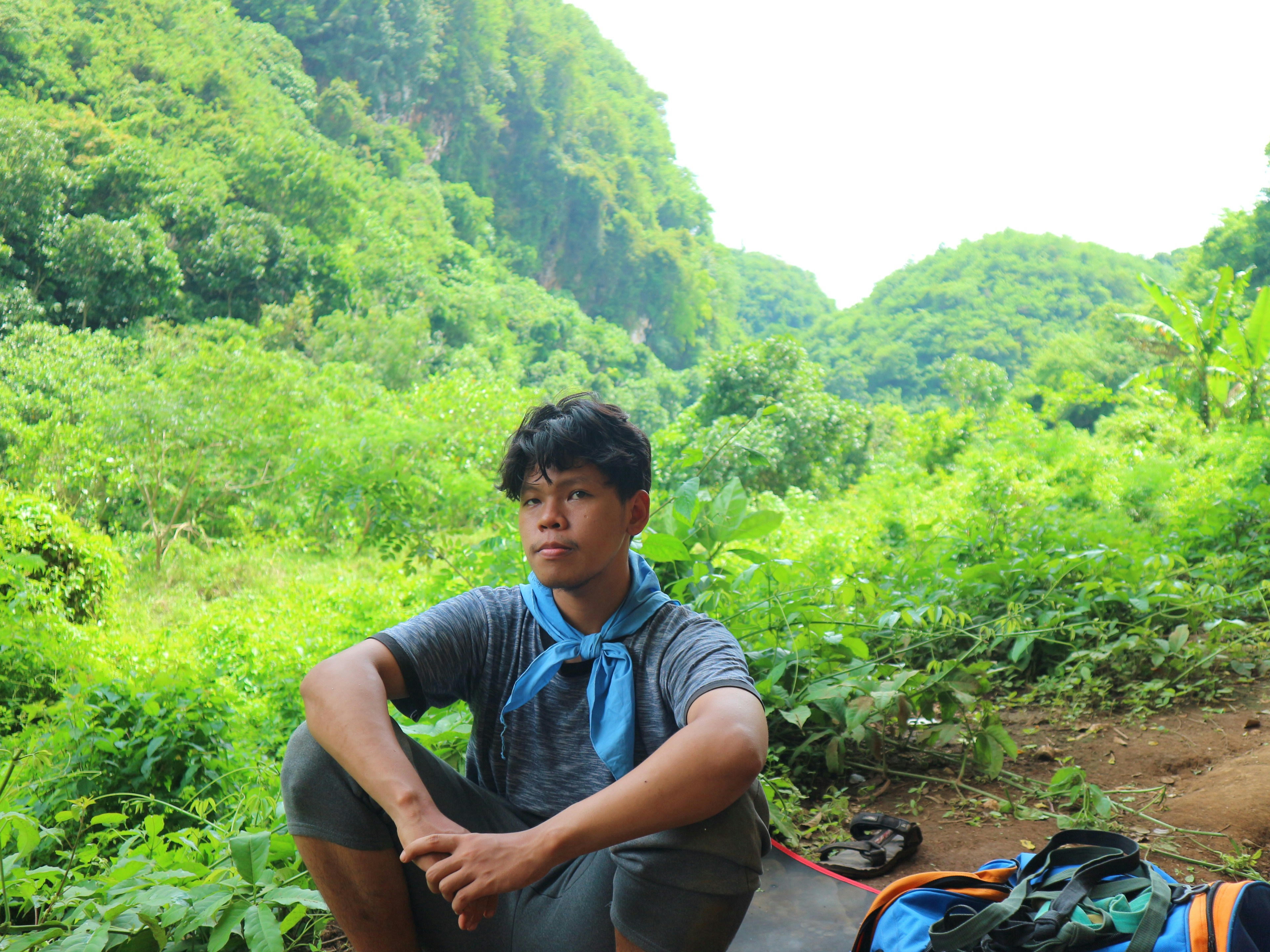 a man sitting on the ground next to a backpack