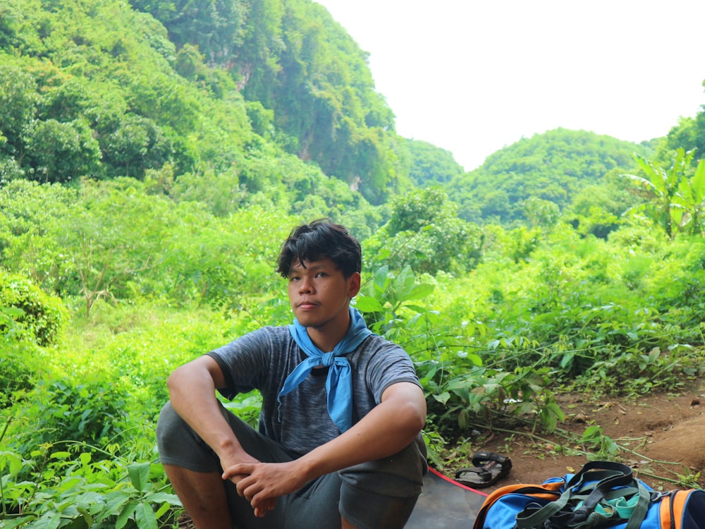 a man sitting on the ground next to a backpack