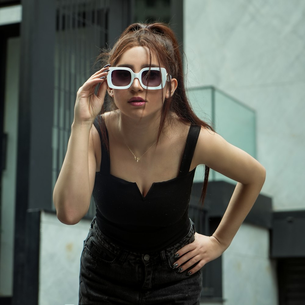 a woman wearing white sunglasses and a black top
