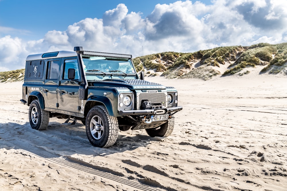 Ein schwarzer Land Rover an einem Sandstrand