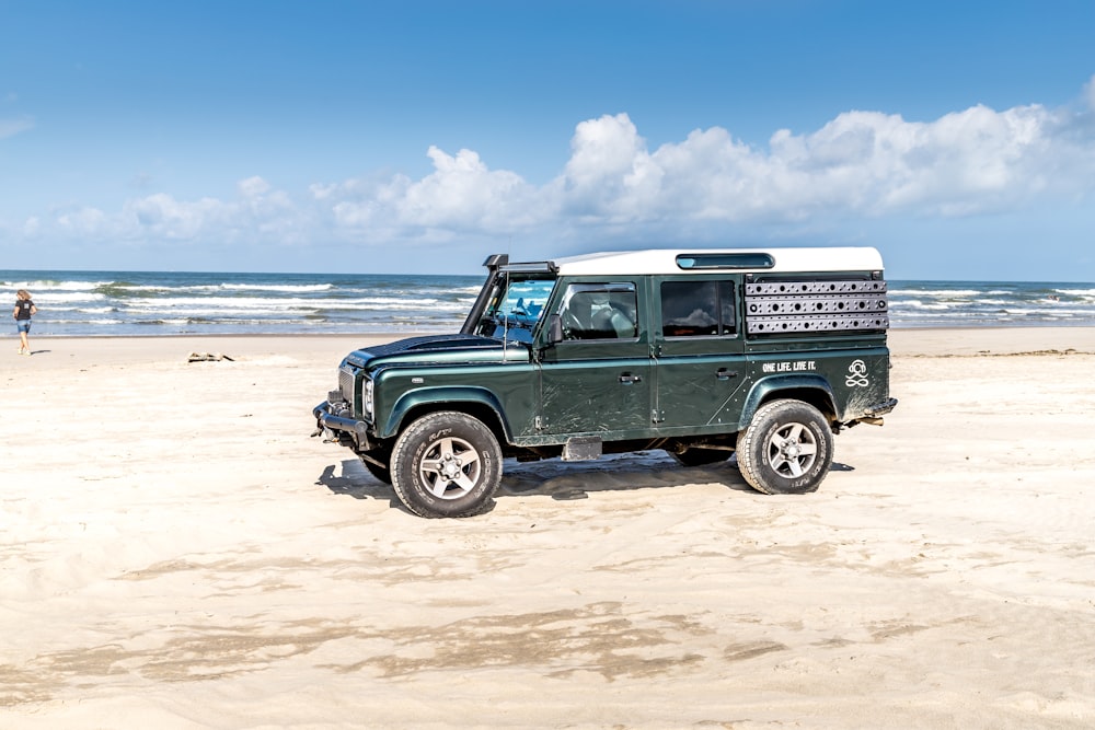 a green truck parked on top of a sandy beach