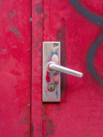 a door handle on a red door with graffiti on it
