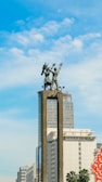 a statue of a man riding a horse in front of a tall building