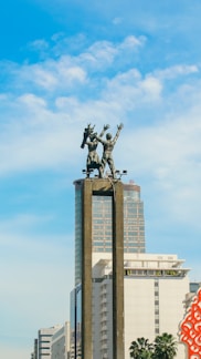a statue of a man riding a horse in front of a tall building