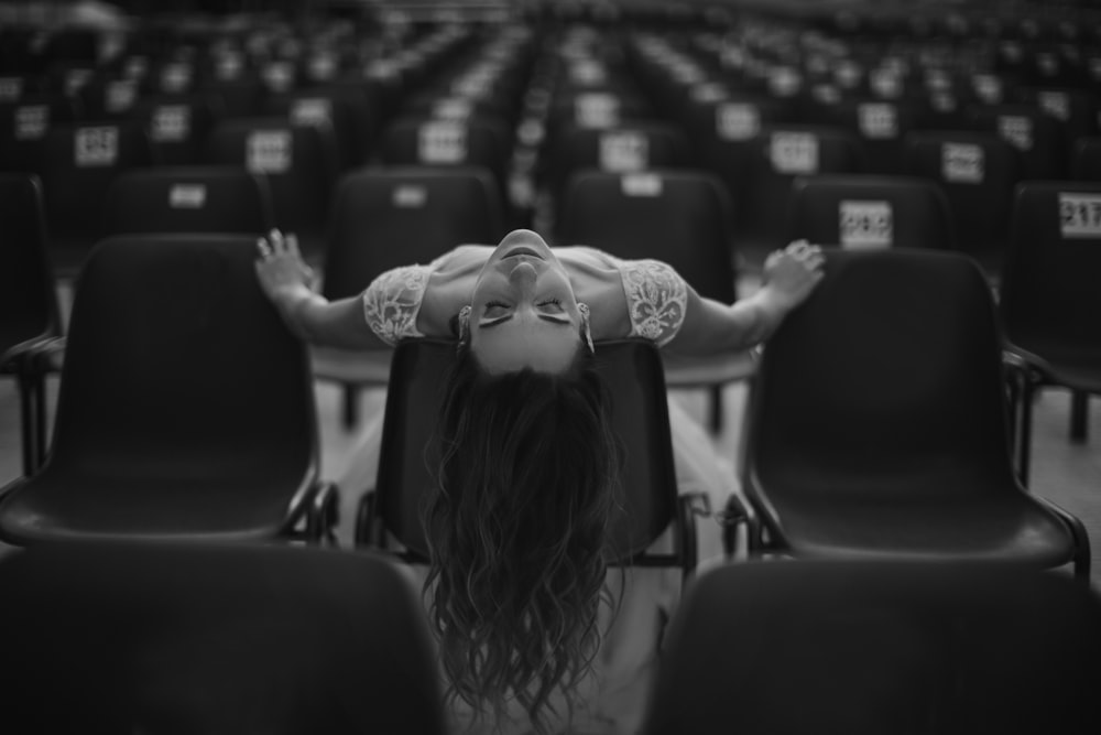a woman laying on a chair in a room full of empty chairs