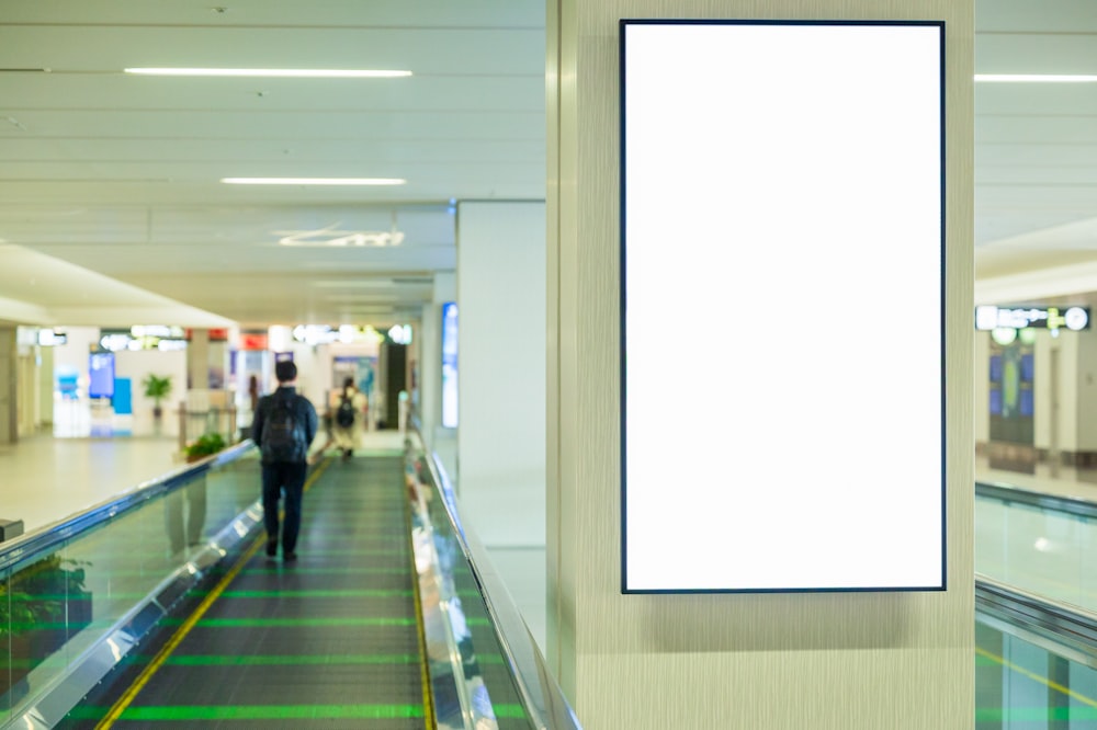 a man is walking down an escalator with a sign