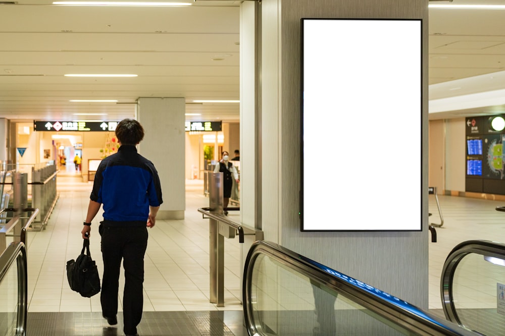 a man walking down an escalator carrying a bag