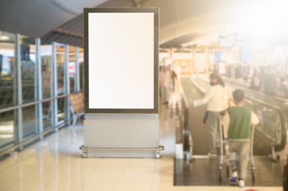 an empty sign in an airport with people in the background