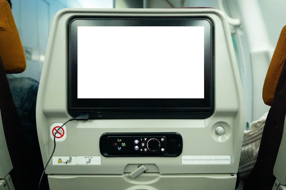 a computer monitor sitting on top of an airplane seat