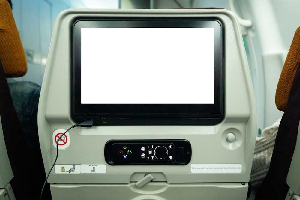 un monitor di computer seduto sopra un sedile di un aereo
