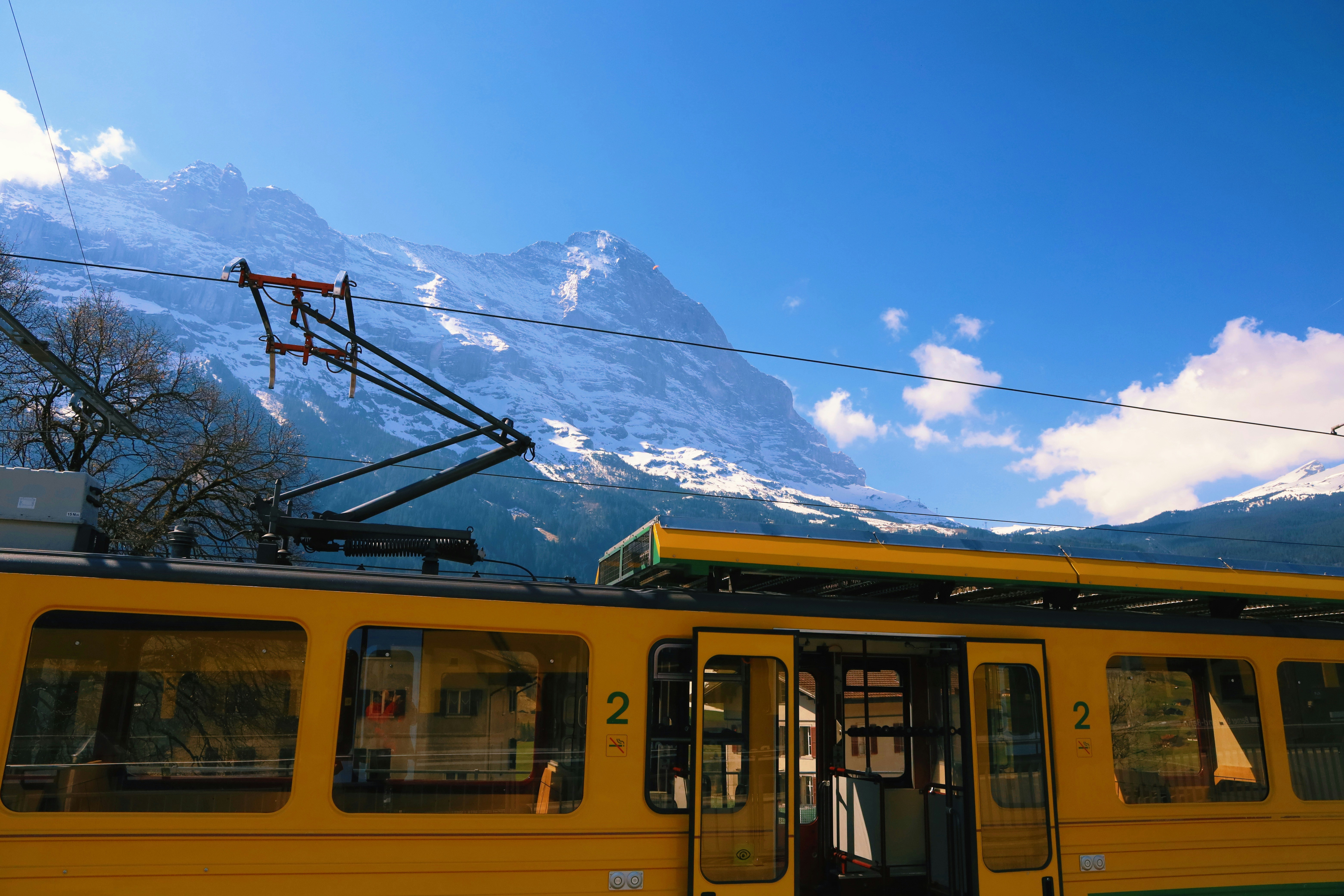 a yellow train with mountains in the background, 