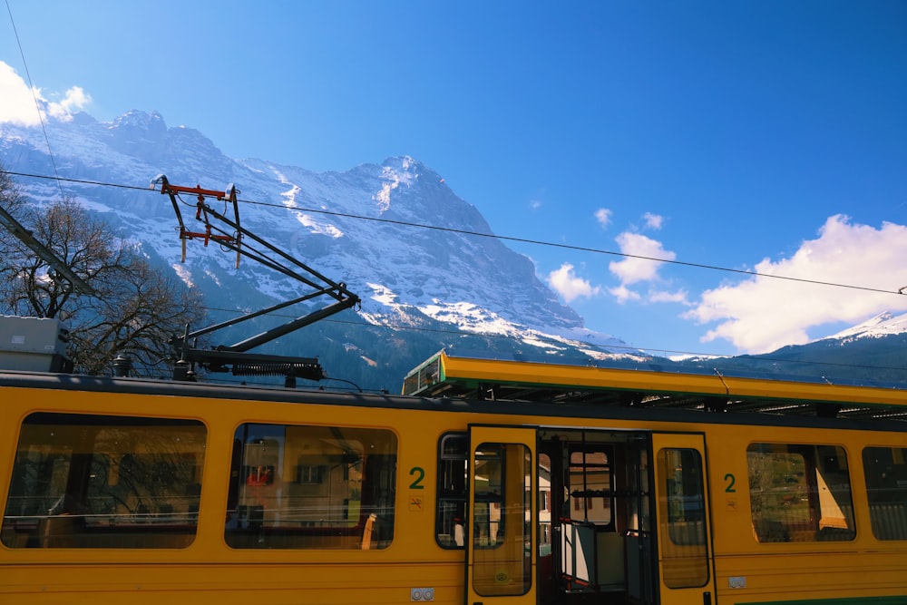a yellow train with mountains in the background