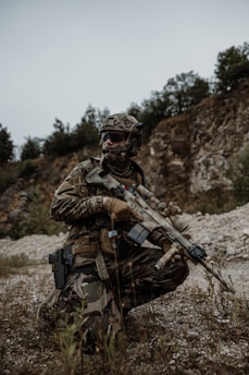 a man kneeling down with a rifle in his hand
