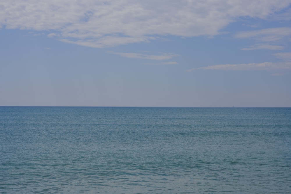 a large body of water sitting under a cloudy blue sky