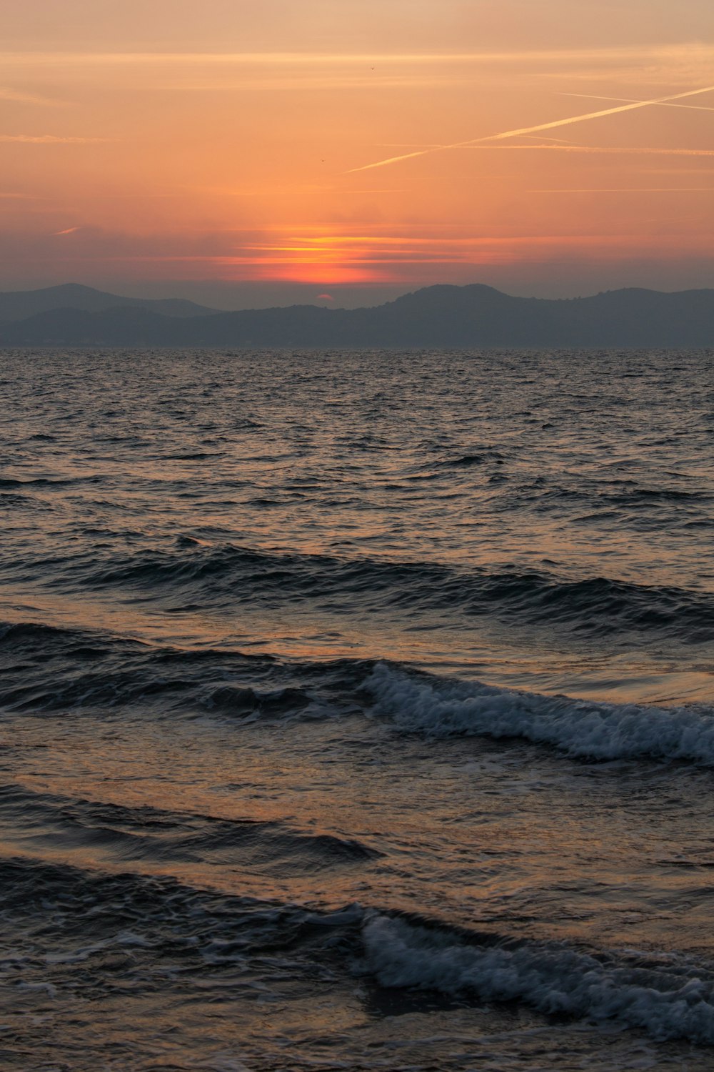 the sun is setting over the ocean with waves