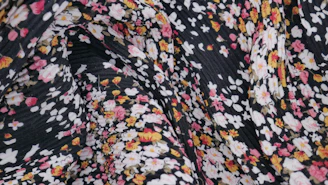 A close-up of a delicate block print pattern on soft pastel pink fabric.