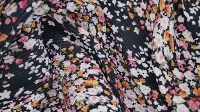 A close-up of a delicate block print pattern on soft pastel pink fabric.