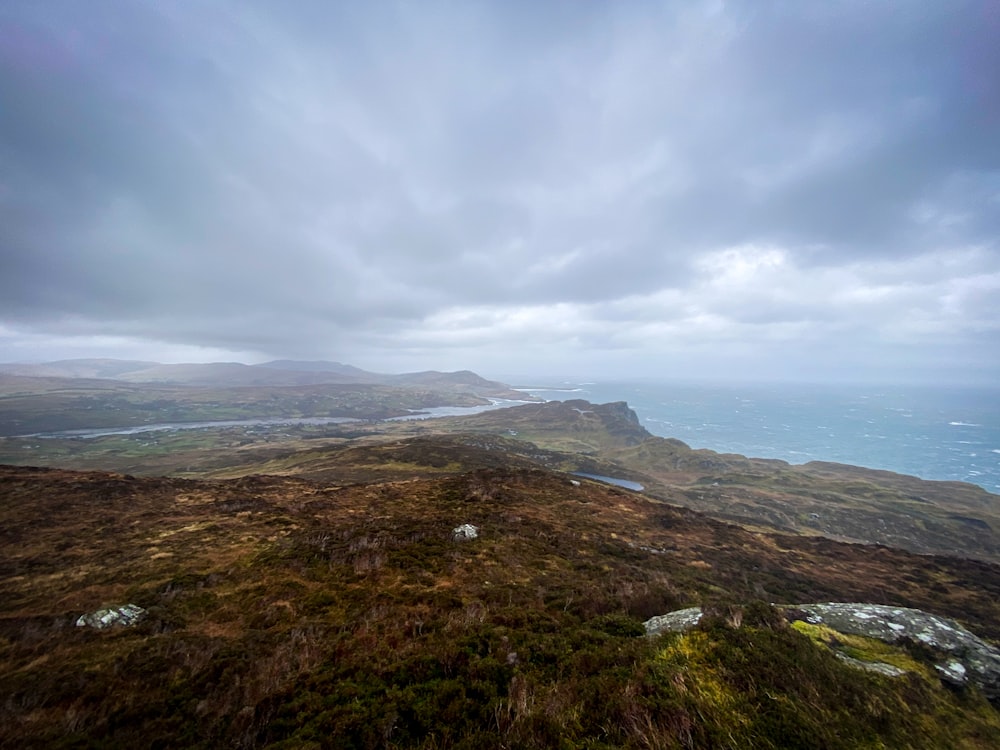 a grassy hill with a body of water in the distance