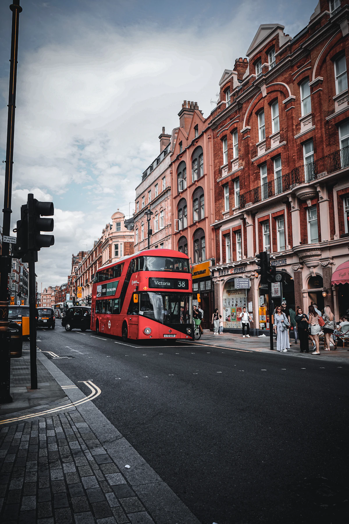 A red double-decker bus travelling through a London street