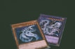 Two trading cards from a collectible card game are displayed with a dragon theme. One card features the title 'Cyber Dragon', presenting an image of a metallic dragon with blue and silver hues. The second card, partially visible, also depicts a dragon with dynamic artwork involving purple and blue lightning effects.
