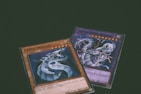 Two trading cards from a collectible card game are displayed with a dragon theme. One card features the title 'Cyber Dragon', presenting an image of a metallic dragon with blue and silver hues. The second card, partially visible, also depicts a dragon with dynamic artwork involving purple and blue lightning effects.