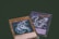 Two trading cards from a collectible card game are displayed with a dragon theme. One card features the title 'Cyber Dragon', presenting an image of a metallic dragon with blue and silver hues. The second card, partially visible, also depicts a dragon with dynamic artwork involving purple and blue lightning effects.