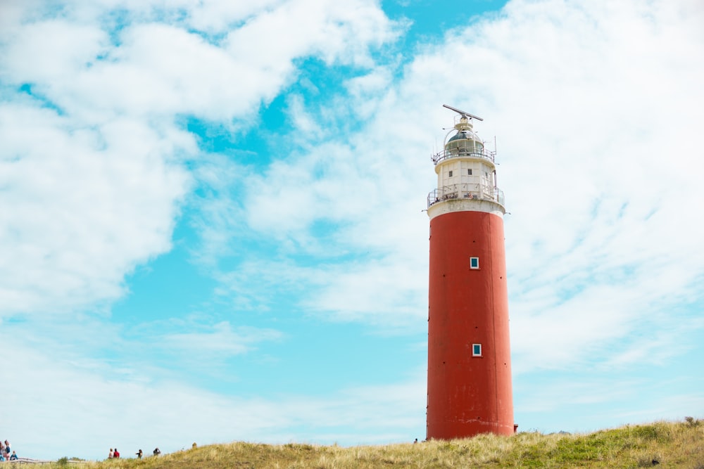 a red and white light house sitting on top of a hill