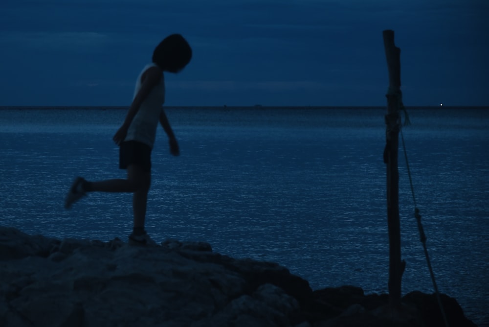 a person standing on a rock near the ocean