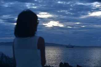 a woman looking at a boat in the ocean
