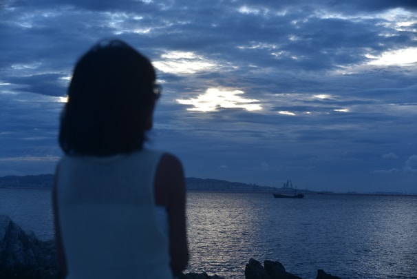 a woman looking at a boat in the ocean