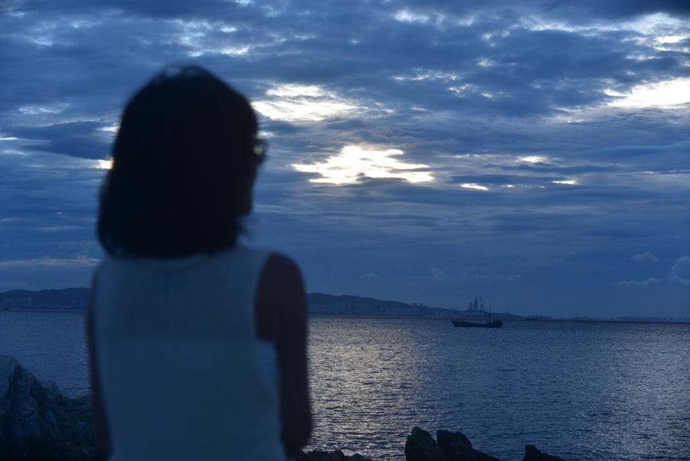 a woman looking at a boat in the ocean