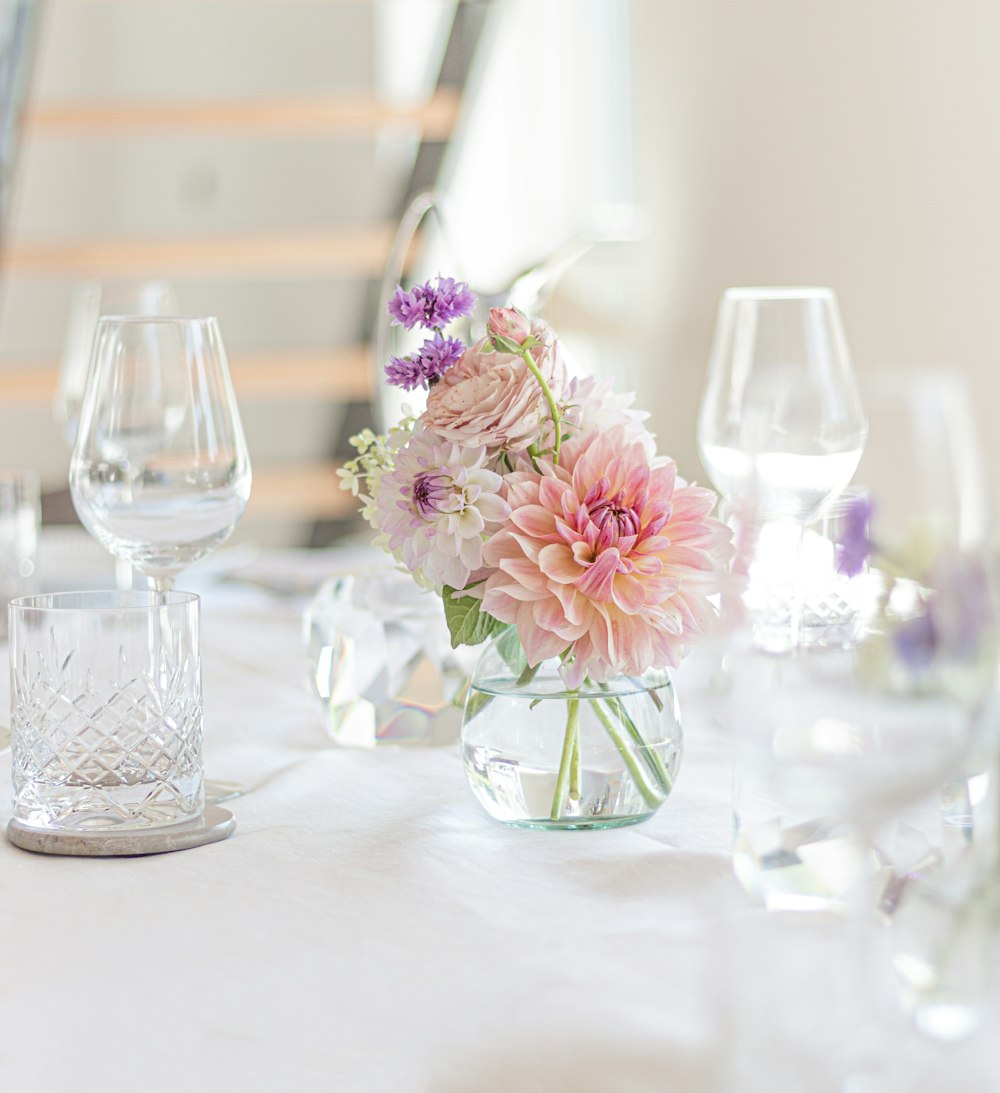 a table with a vase of flowers and wine glasses