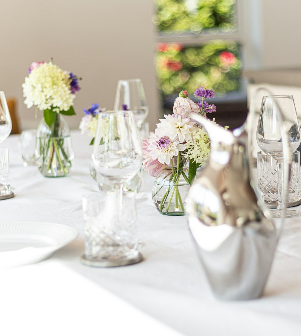 a white table topped with lots of glass vases filled with flowers
