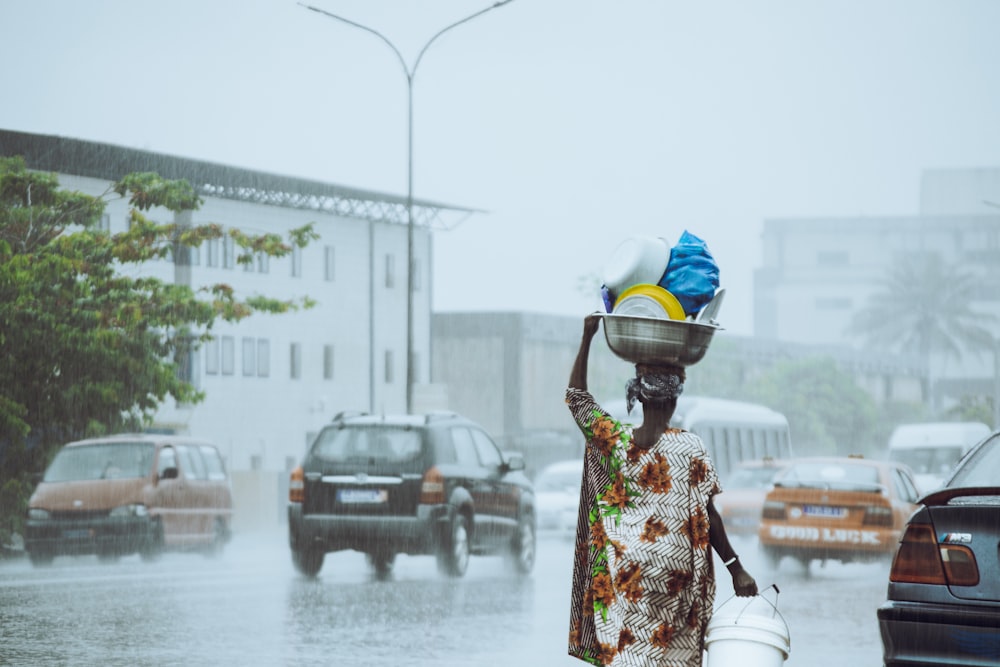 a woman carrying a bucket on her head in the rain