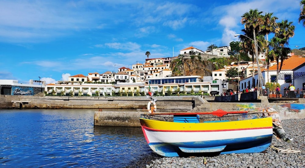 a colorful boat sitting on the shore of a body of water