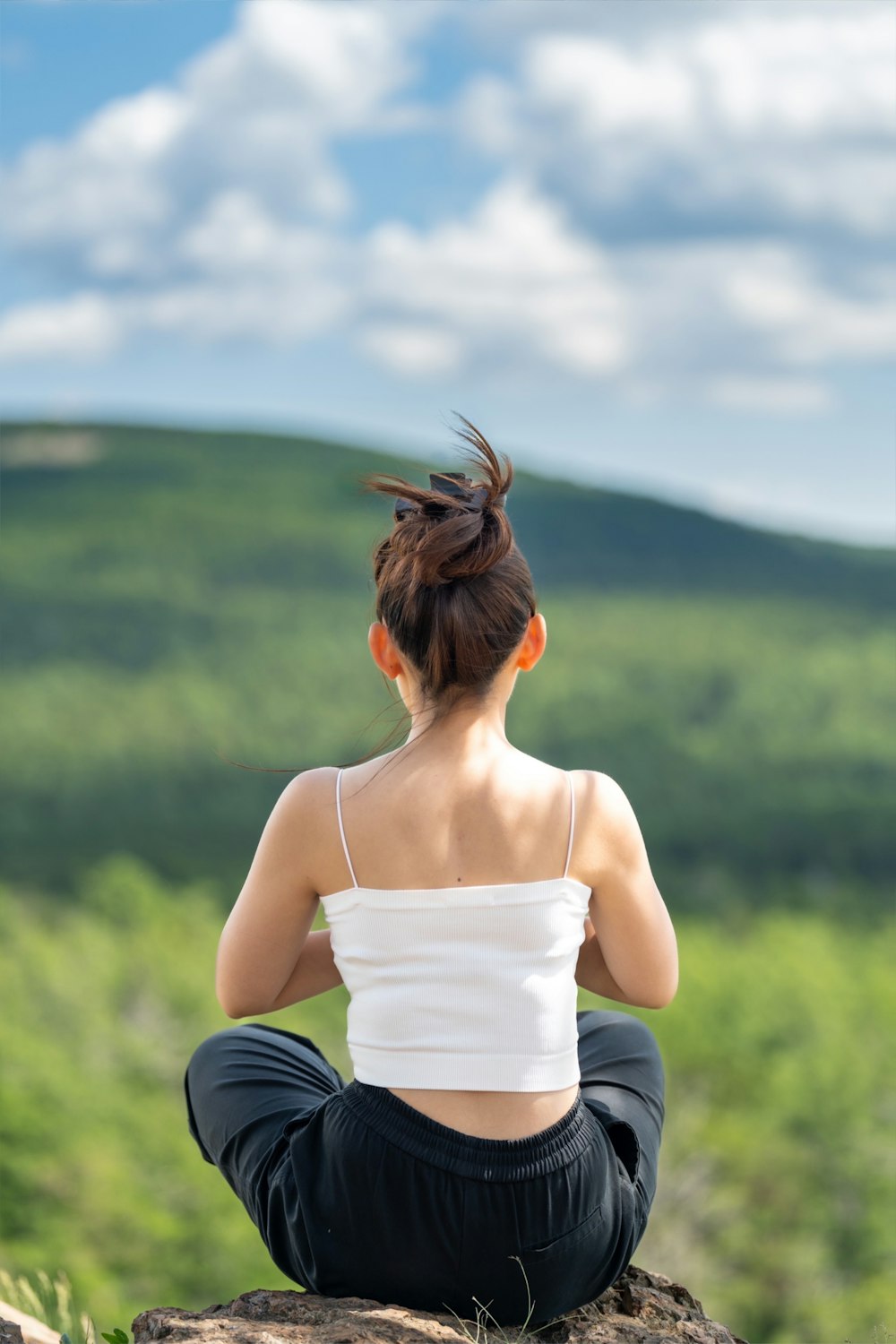 a woman sitting on top of a rock with her hair in the air