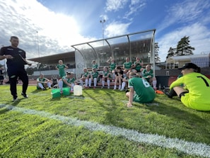 Sports team in dry green and beige athletic uniforms posing on a sunlit field