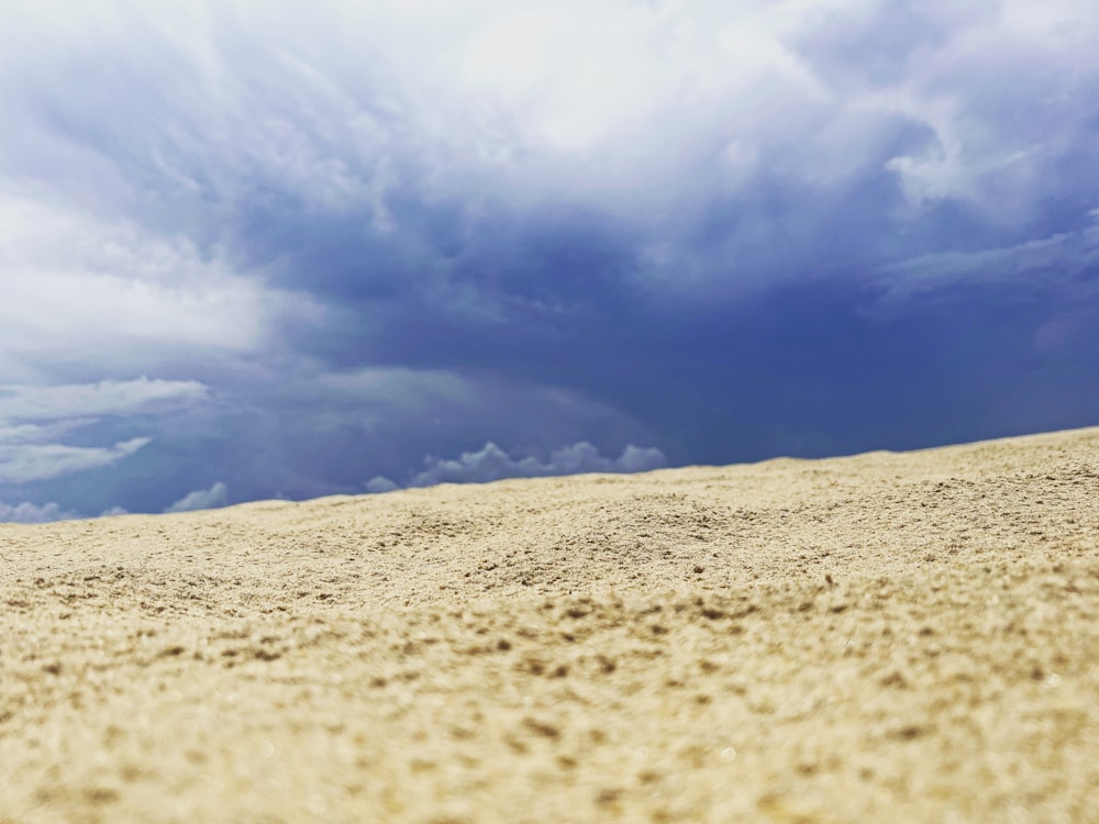 a sandy beach under a cloudy blue sky