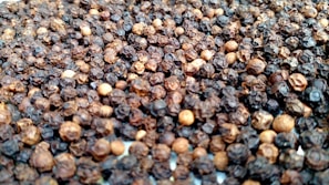 Close-up of rich, glossy black peppercorns spilling from a rustic burlap sack.