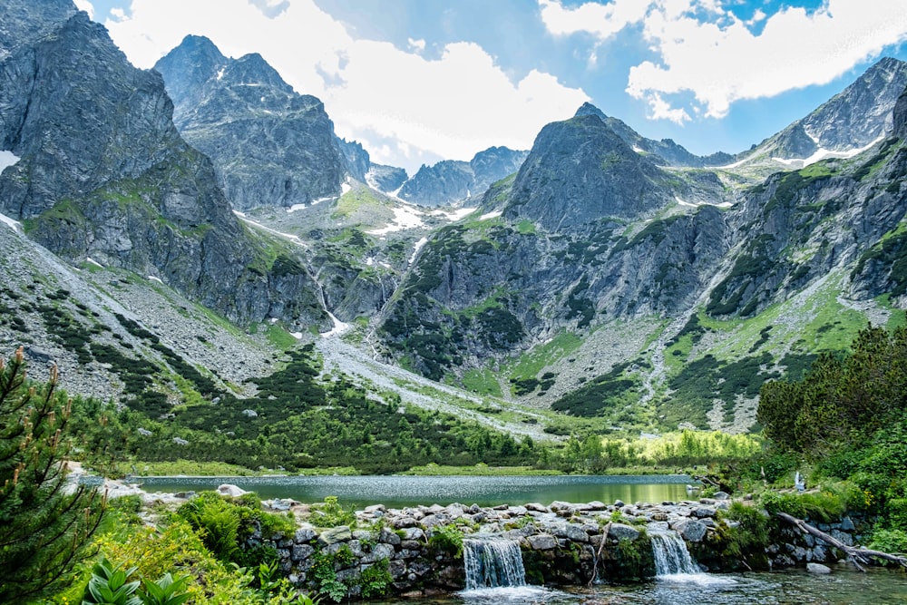 a mountain range with a small waterfall in the foreground