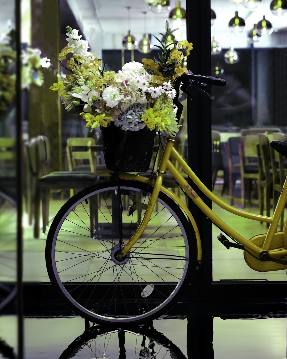 a yellow bicycle with a basket full of flowers