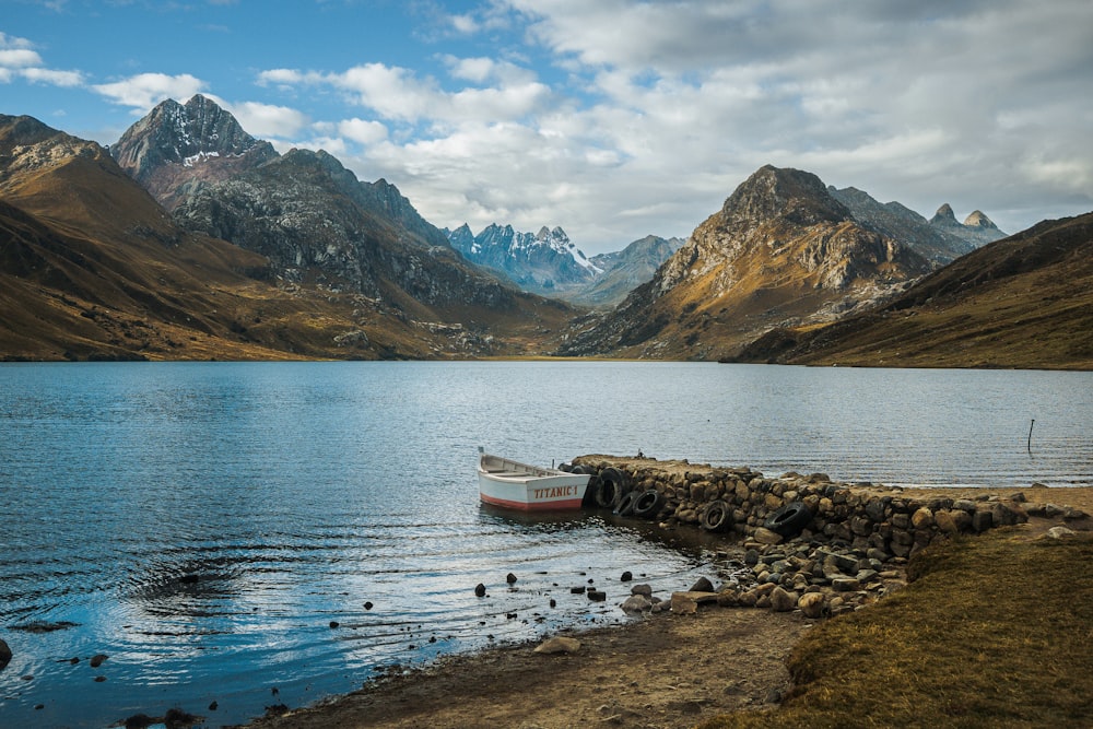 a boat sitting on top of a lake surrounded by mountains