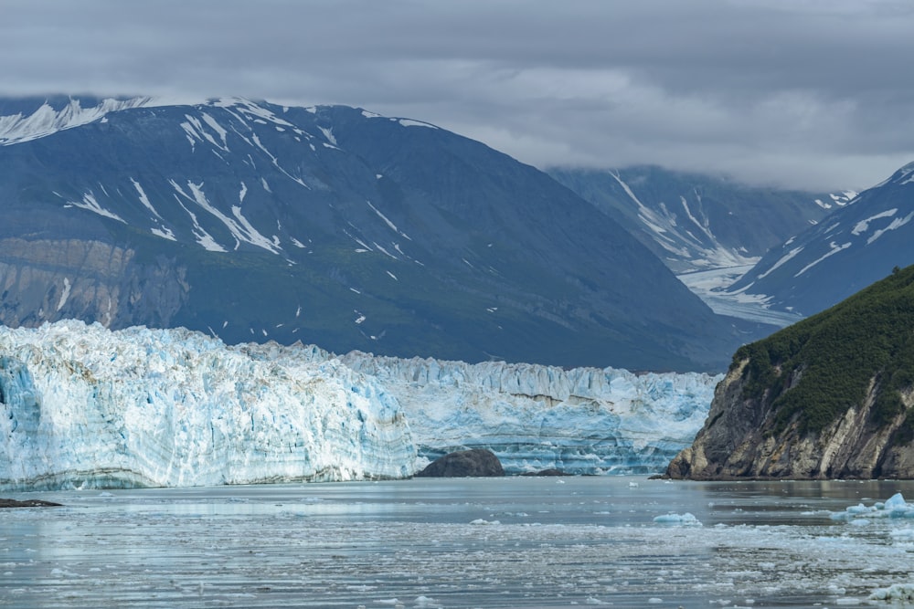 a large glacier with mountains in the background