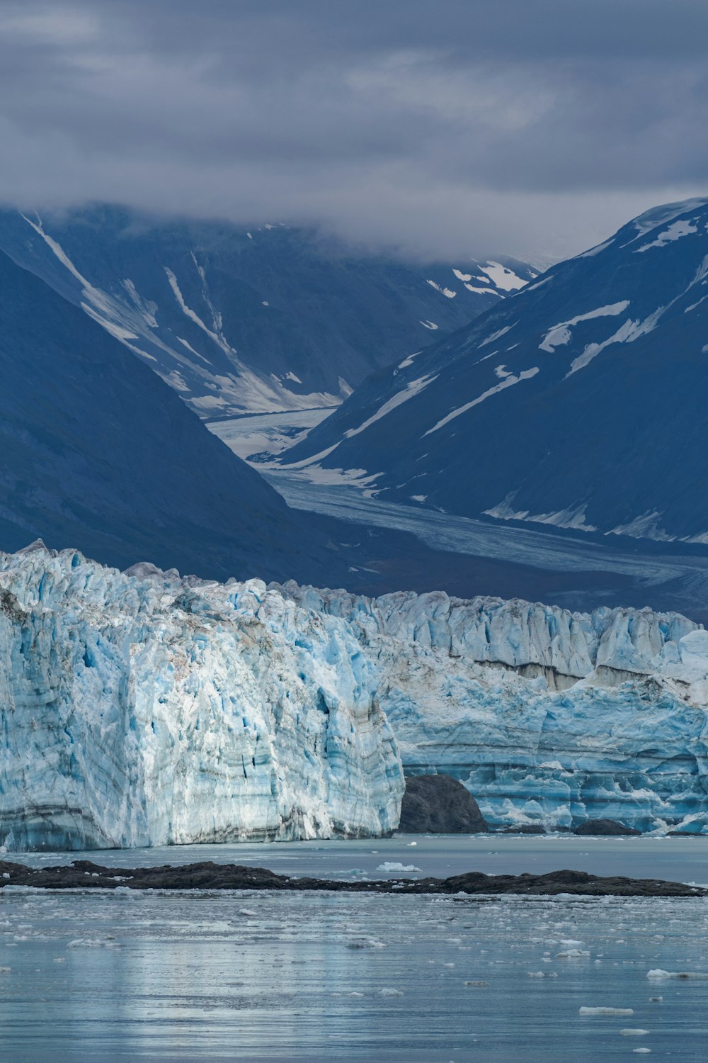 a large glacier with mountains in the background