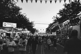 A bustling street fair with food stalls and families having fun.