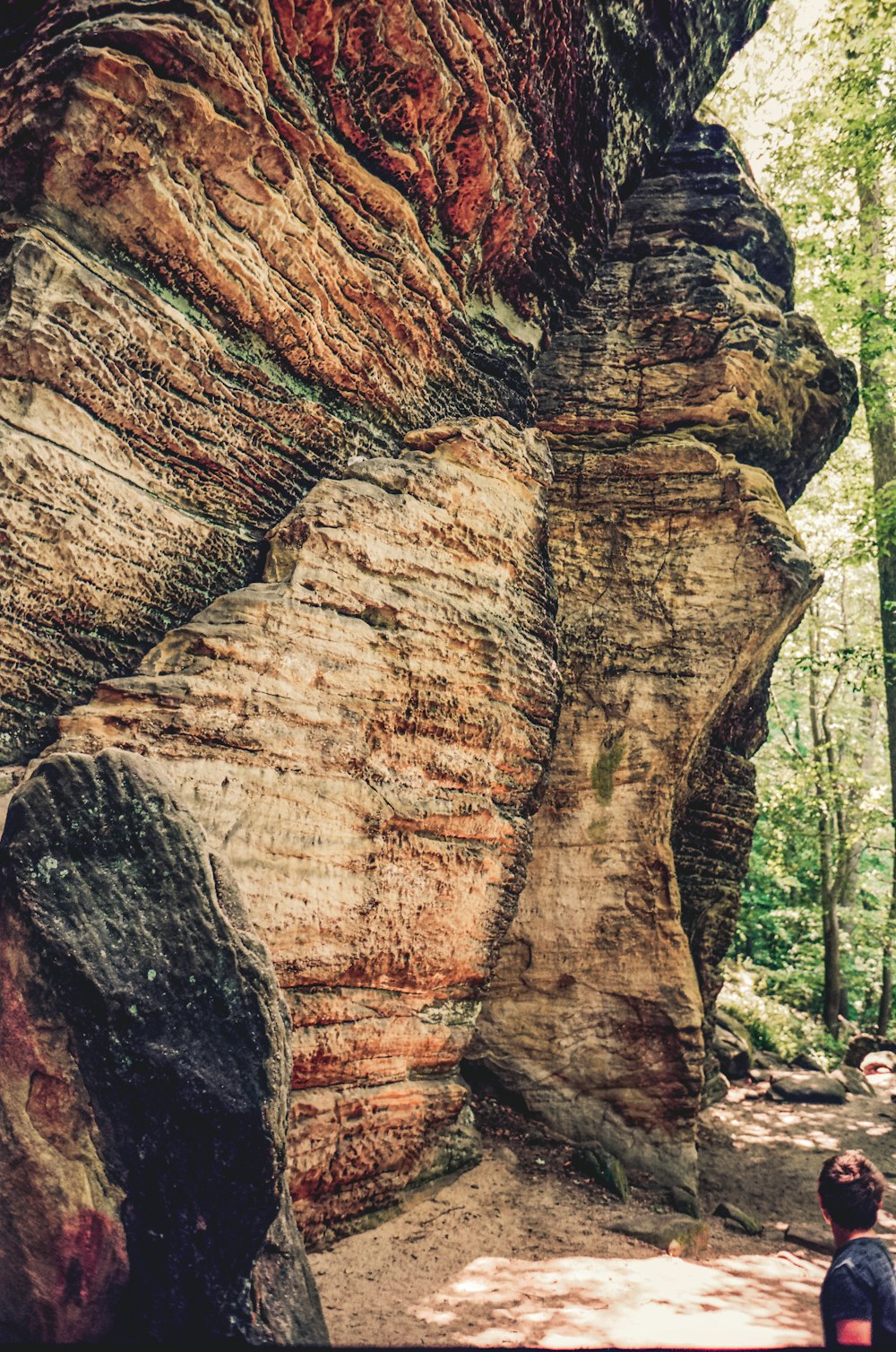 una persona in piedi di fronte a una grande formazione rocciosa