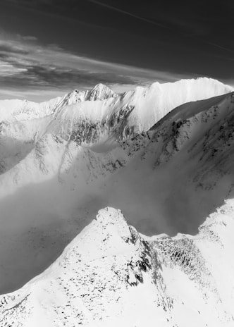 Black and white photo capturing a quiet mountain range with sharp peaks and deep shadows.
