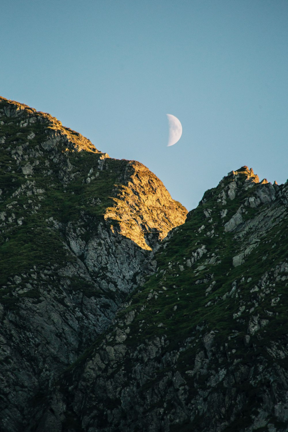 the moon is setting over a mountain range