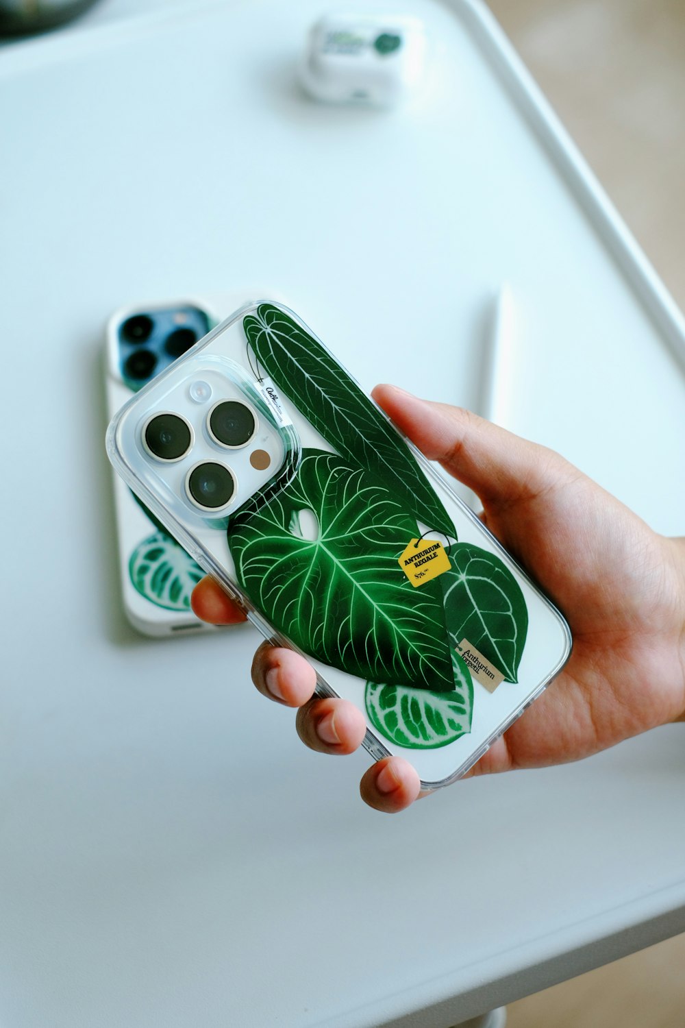 a person holding a phone case with a green leaf on it
